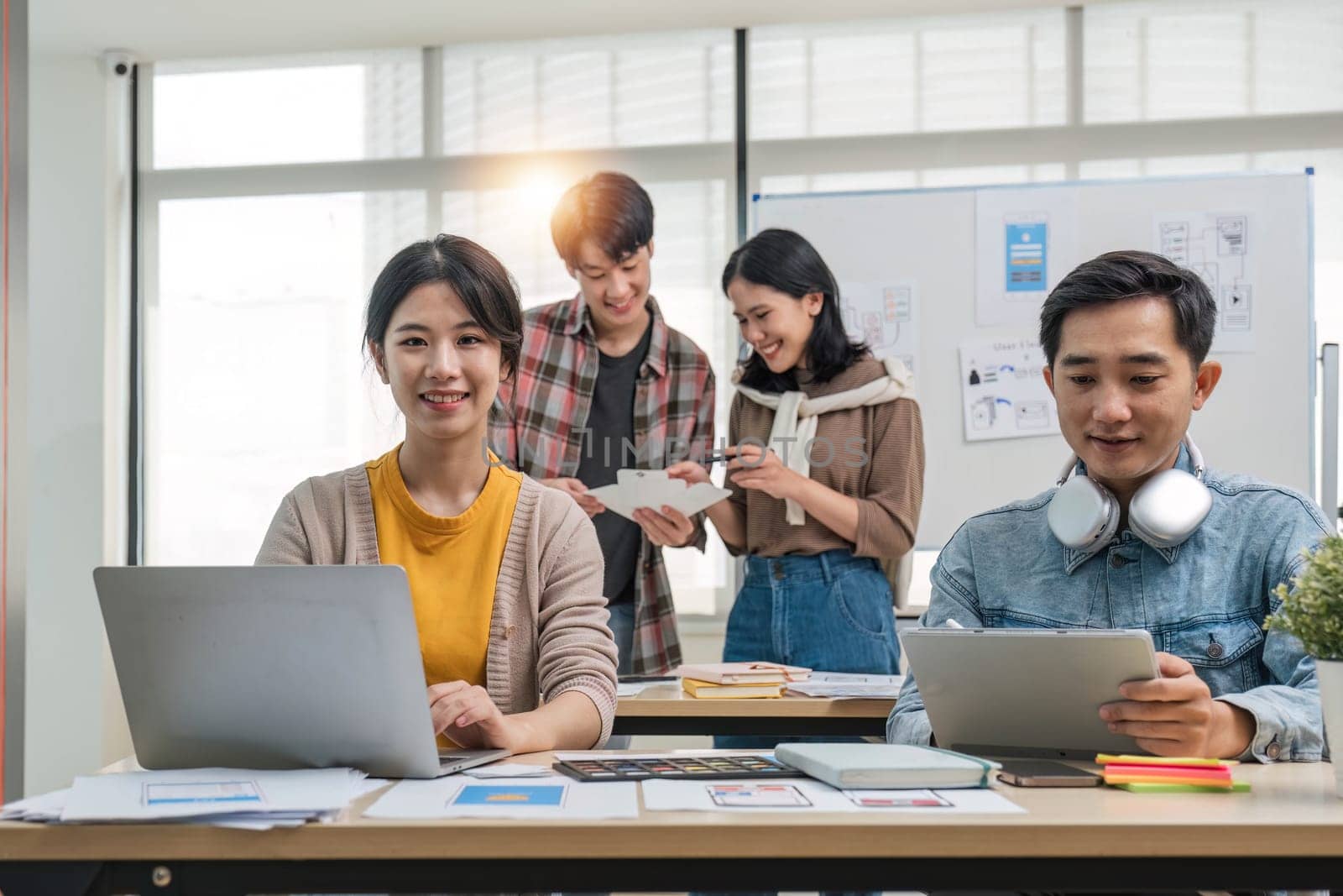 A group of professional Asian UI, UX graphic designers, or developers is in the meeting, brainstorming and planning a new project together...