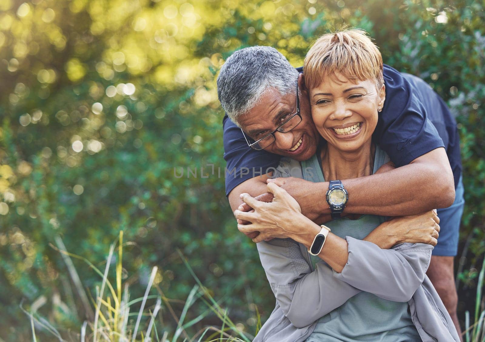 Nature, love and man hugging his wife with care, happiness and affection while on an outdoor walk. Happy, romance and portrait of a senior couple in retirement embracing in the forest, woods or park
