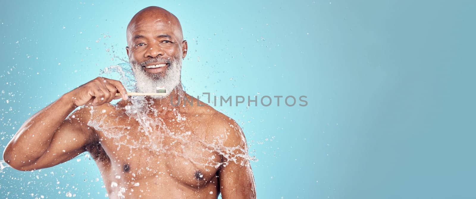 Water splash, dental and black man with toothbrush, mockup and smile on face isolated on blue background space. Teeth, toothpaste and product placement, happy senior in studio portrait cleaning mouth by YuriArcurs
