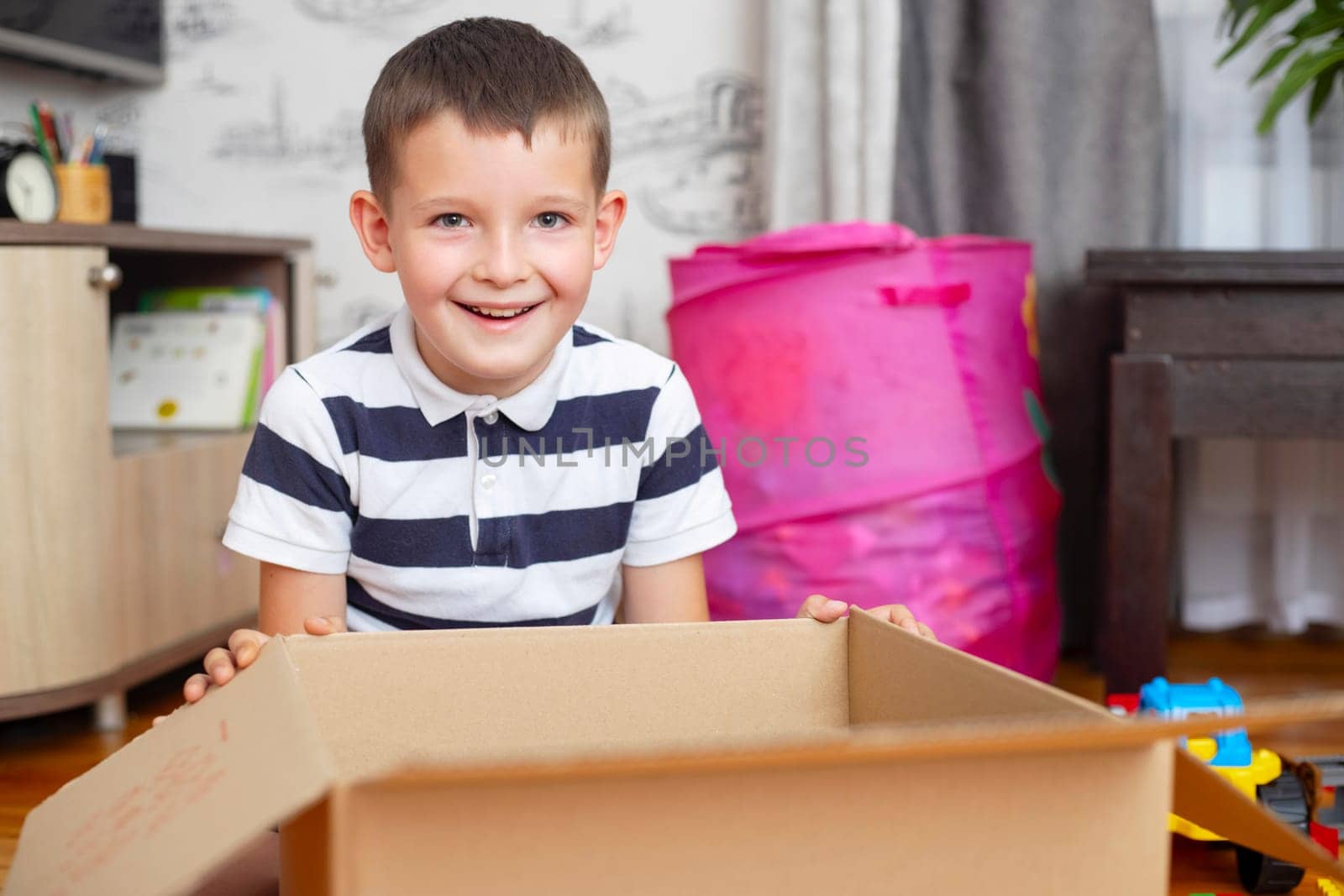 A boy is unpacking cardboard box ( gift box or parcel) at home. Delivery and service concept. Online shopping.