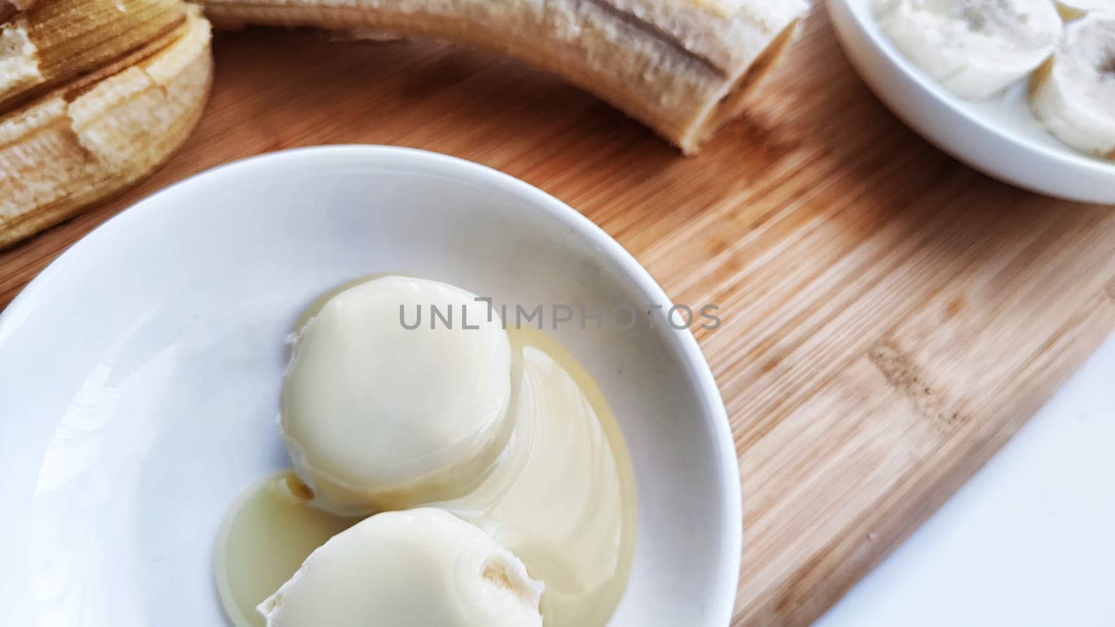 Banana with open panel on wooden board and sliced round pieces on the plate on white background. Ripe banana with peel and cooking. Delicious sweet fruit dessert. Close up