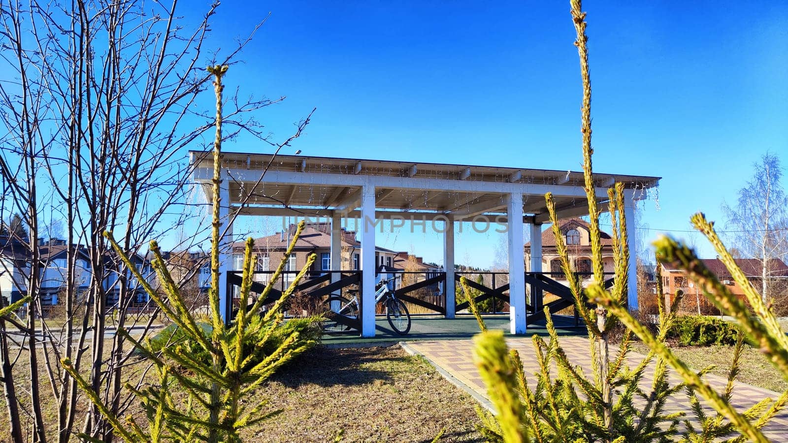Beautiful Wooden gazebo outdoor on Sunny autumn or spring day with blue sky. Early sprint time and pavilion or alcove in village or small town on nature landscape