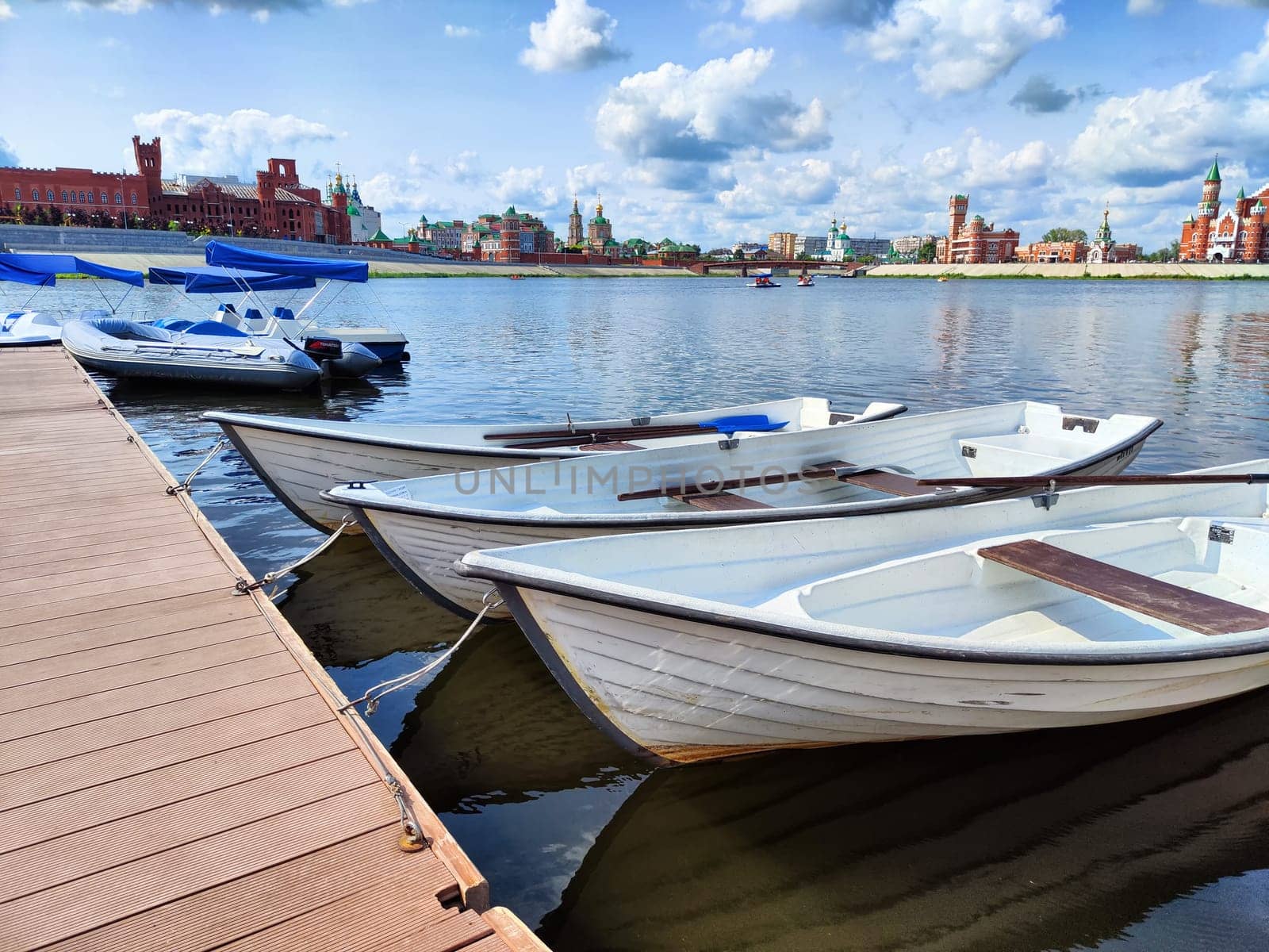 Harbor with wooden boats in city. Embankment of the resort town. Sunny summer day and water landscape in summer