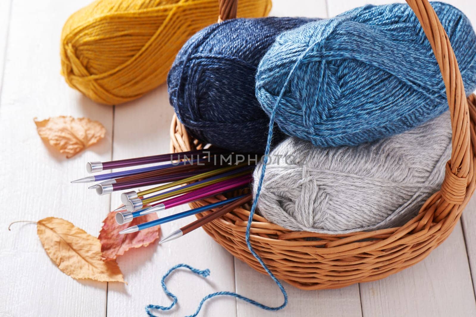Skeins of yarn and knitting needles in basket