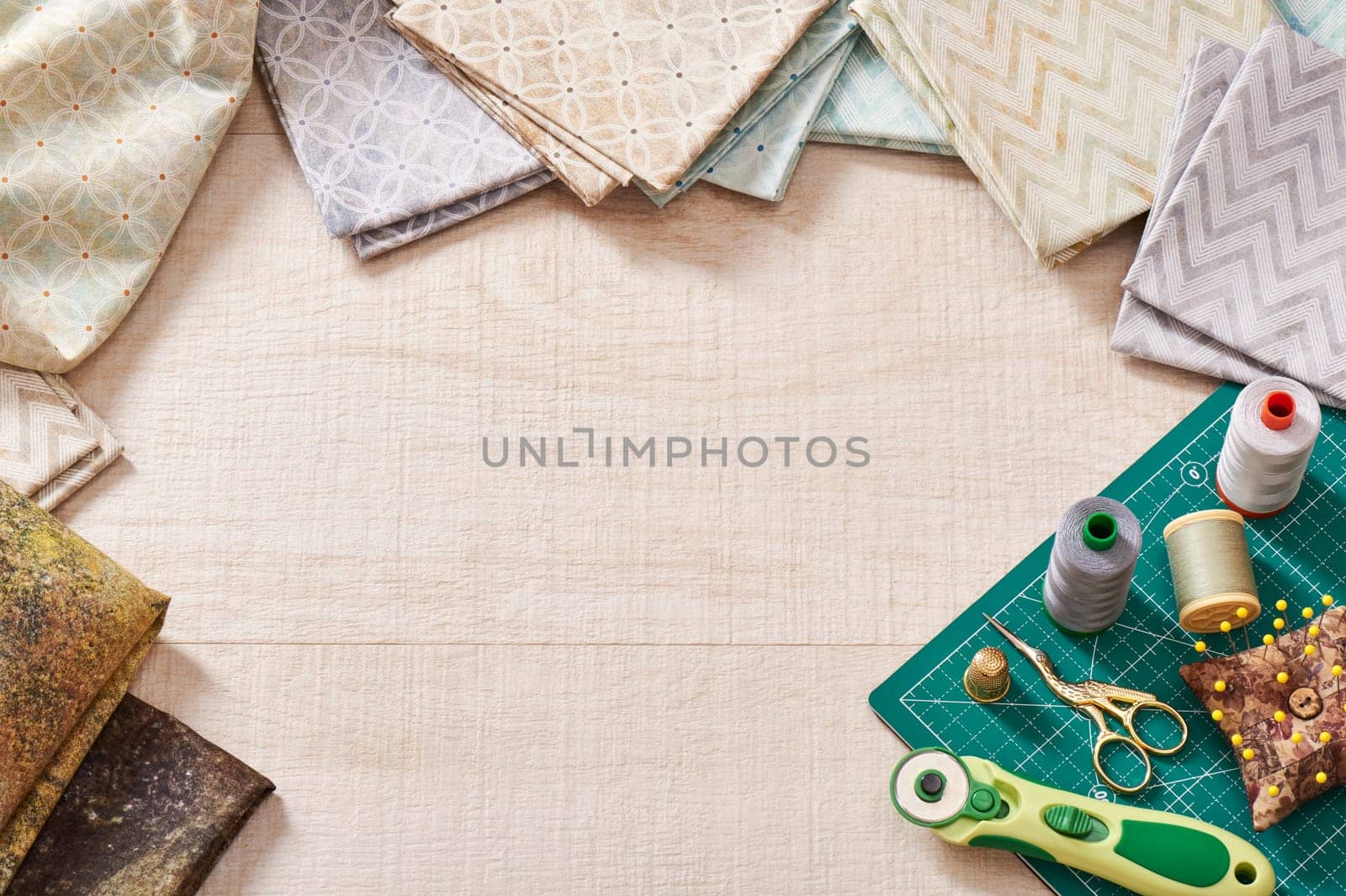 Set of pastel fabrics and sewing tools on craft mat, in center area for text