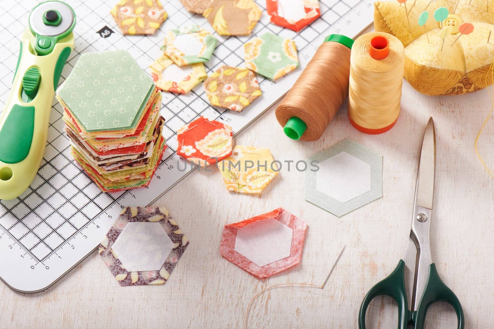 English paper pieced hexagons on white craft mat, sewing equipment
