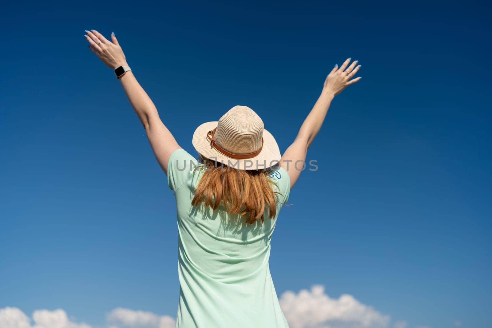 Woman Tourist Sky. Happy traveller woman in hat enjoys vacation raised her hands up by Matiunina