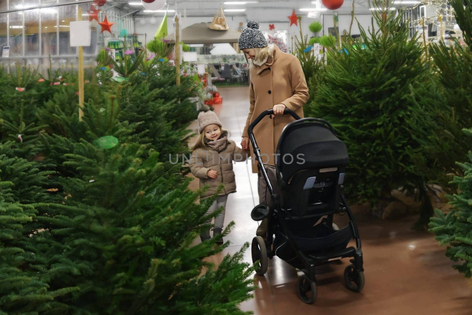 Mother and daughter choose a Christmas tree in the market.