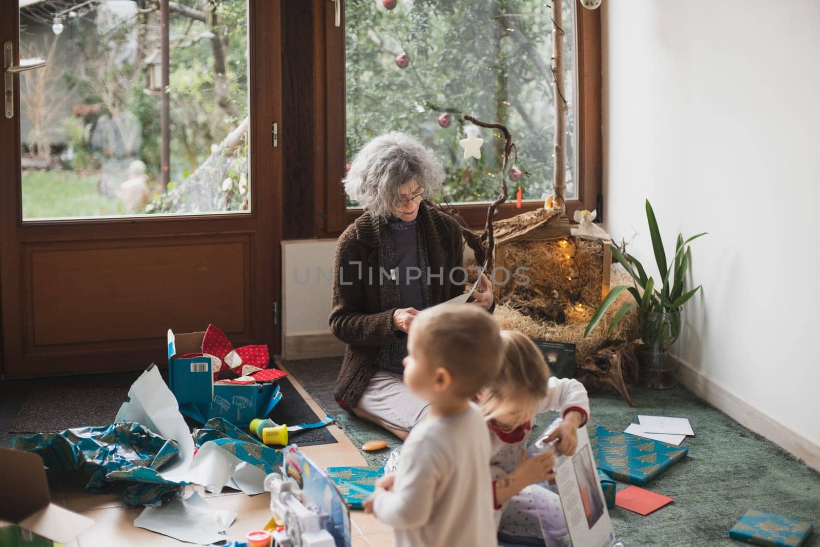 Grandmother and grandchildren open gifts for a Christmas by Godi