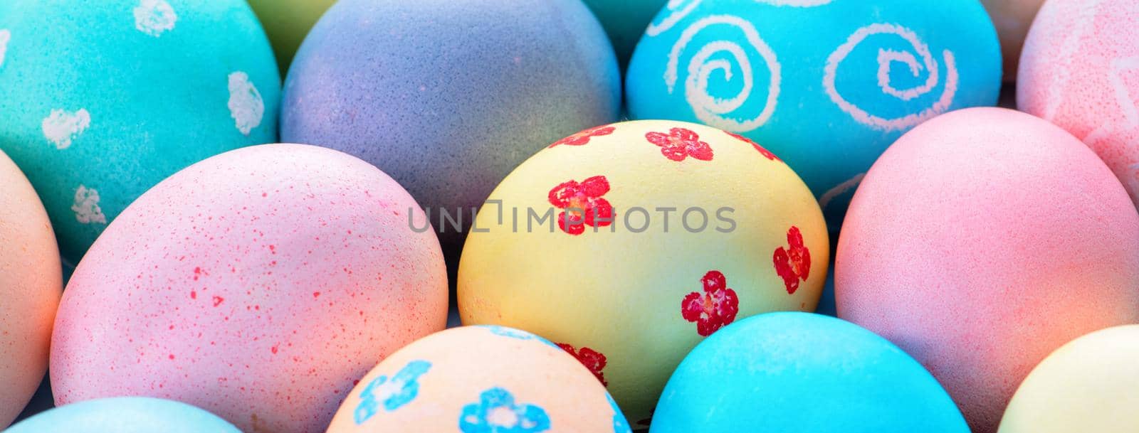 Colorful Easter eggs dyed by colored water with beautiful pattern on a pale blue background, design concept of holiday activity, top view, full frame.