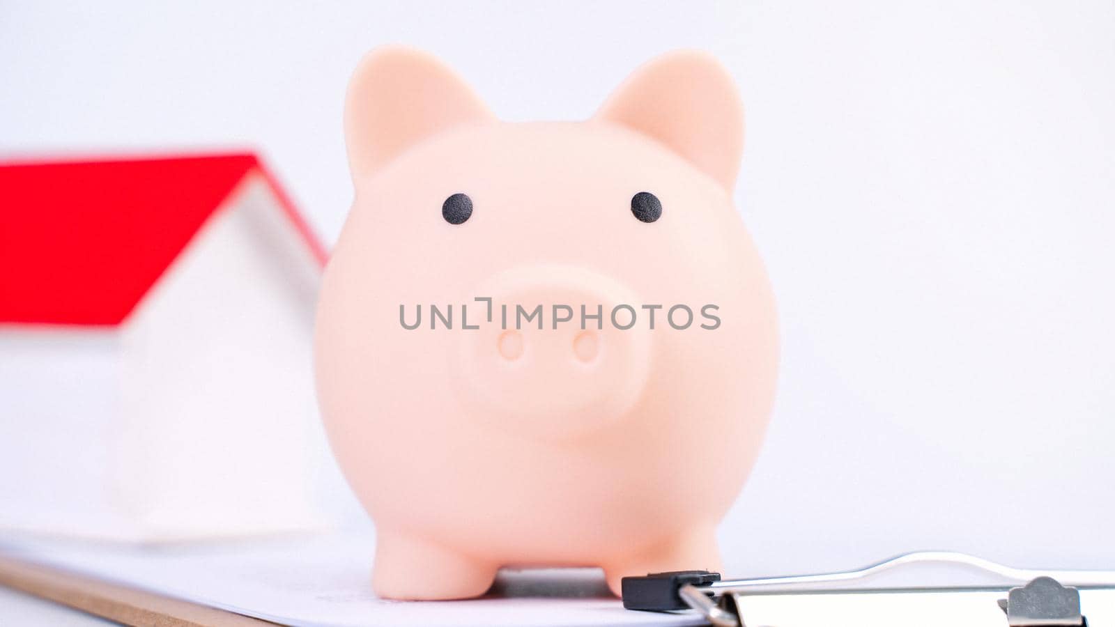 Financial concpet - Piggy bank, beautiful red white wooden house model on white background, saving money to buy insurance, close up, copy space. by ROMIXIMAGE