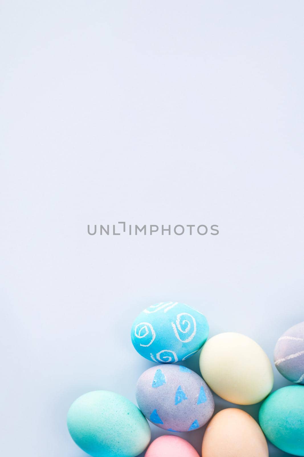 Colorful Easter eggs dyed by colored water with beautiful pattern on a pale blue background, design concept of holiday activity, top view, copy space.