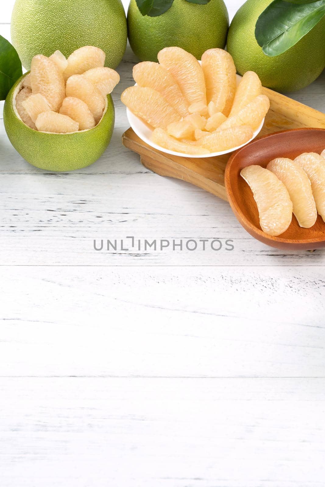 Fresh peeled pomelo, pummelo, grapefruit, shaddock on bright wooden table background. Seasonal fruit for Mid-Autumn Festival, close up, copy space.