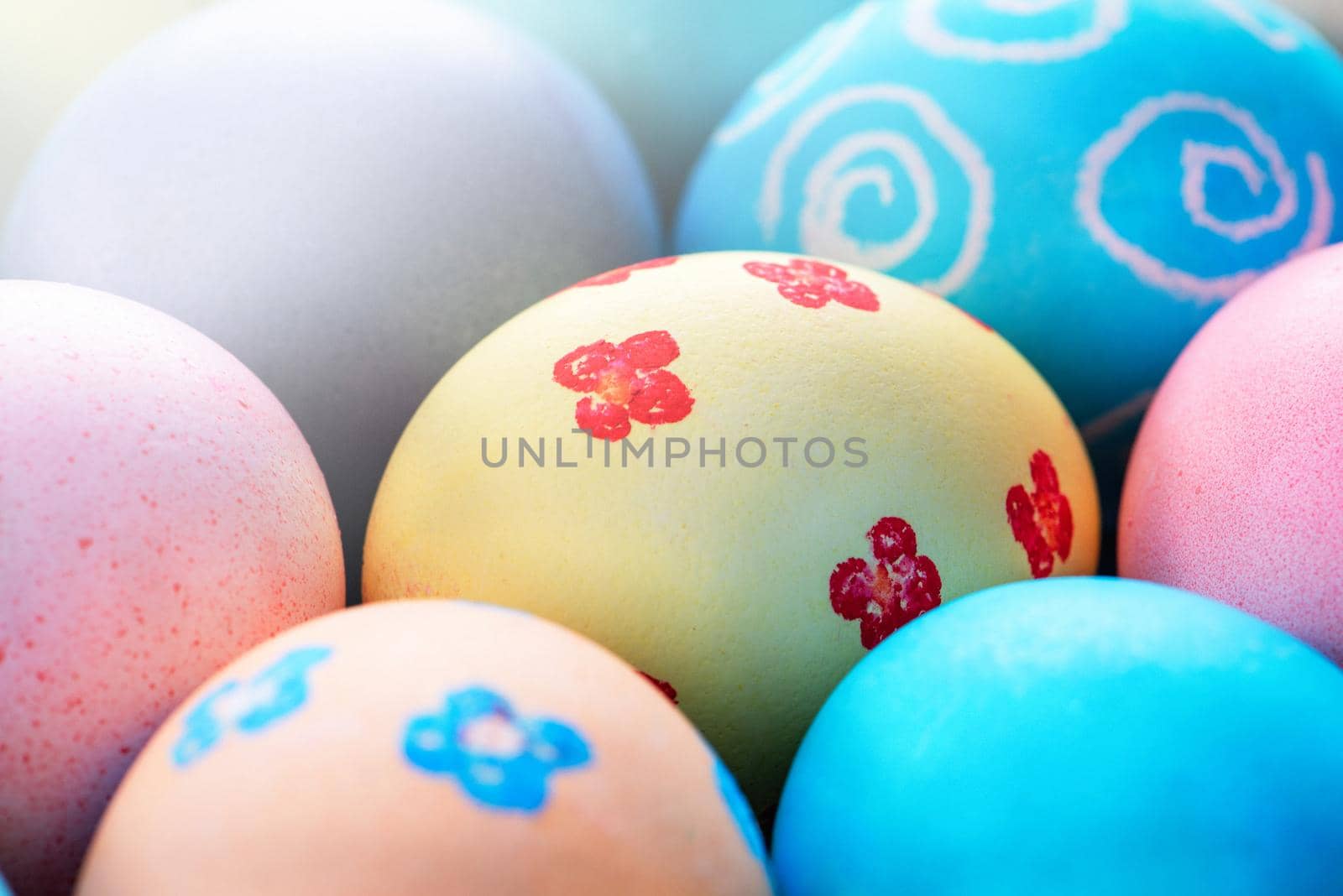 Colorful Easter eggs dyed by colored water with beautiful pattern on a pale blue background, design concept of holiday activity, top view, full frame.