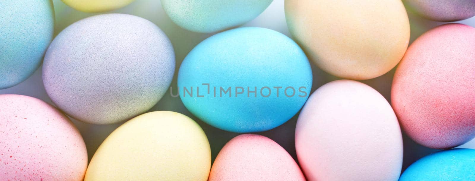 Colorful Easter eggs dyed by colored water with beautiful pattern on a pale blue background, design concept of holiday activity, top view, full frame.