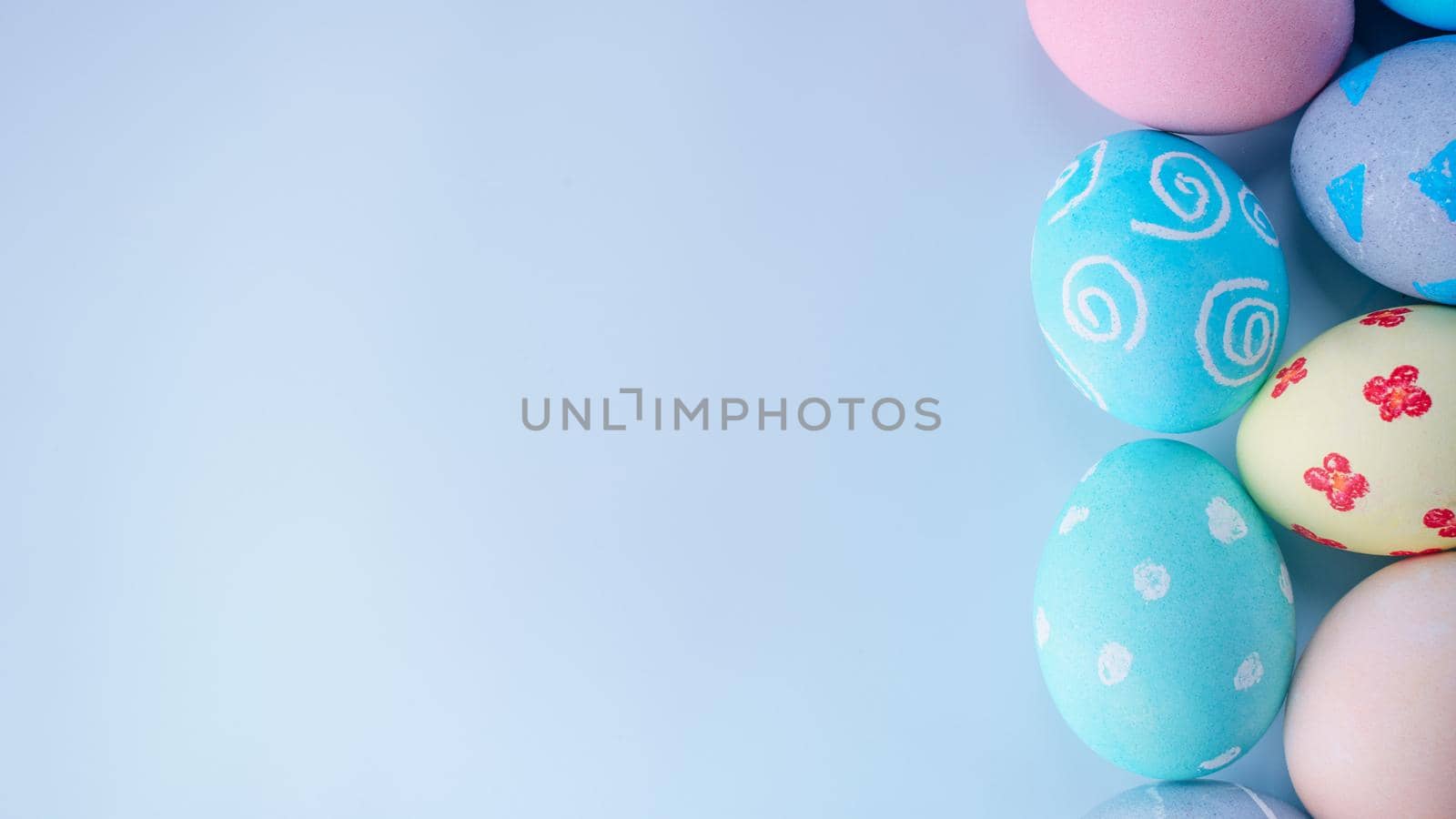 Colorful Easter eggs dyed by colored water with beautiful pattern on a pale blue background, design concept of holiday activity, top view, copy space.