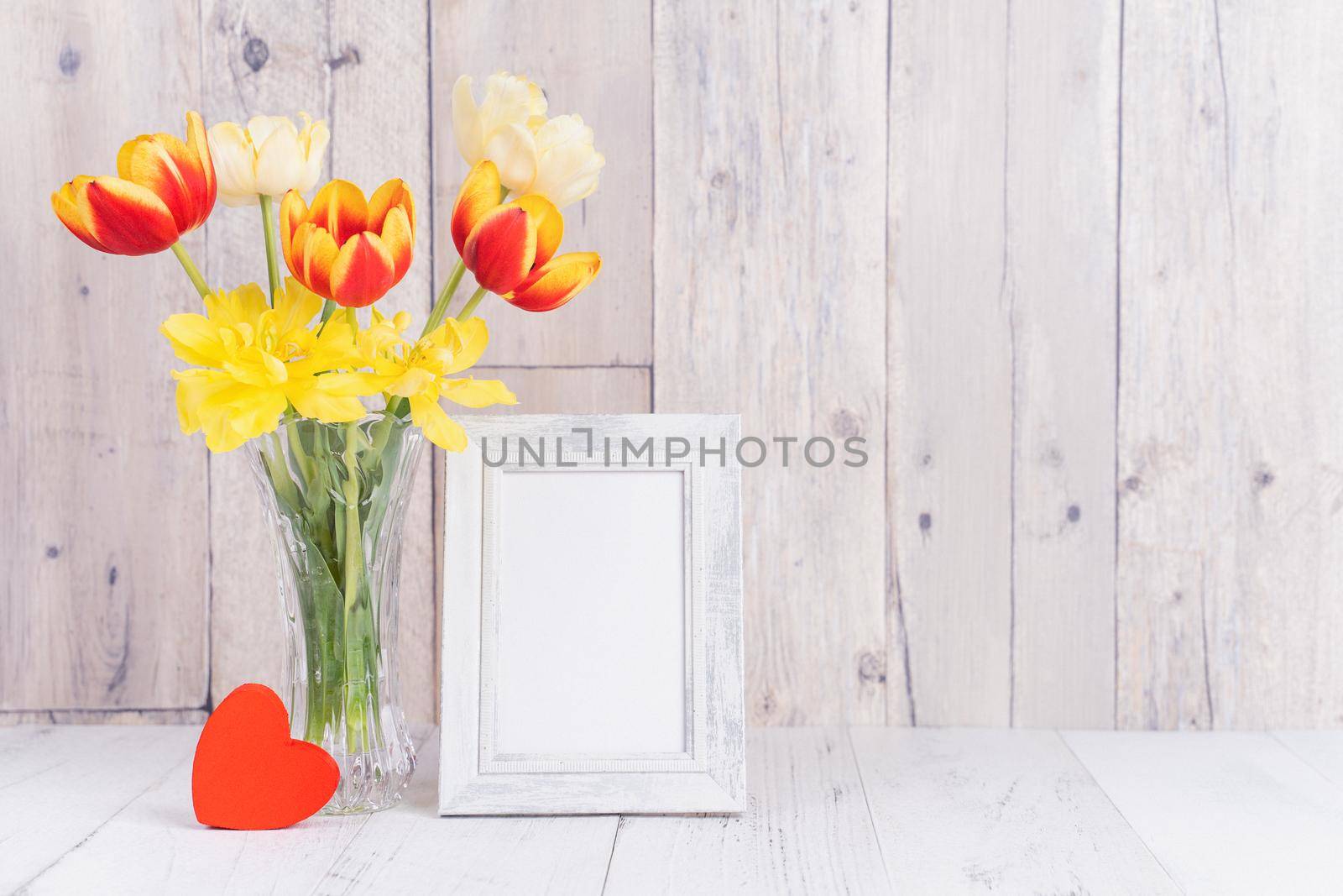 Tulip flower in glass vase with picture frame decor on wooden table background wall at home, close up, Mother's Day design concept. by ROMIXIMAGE