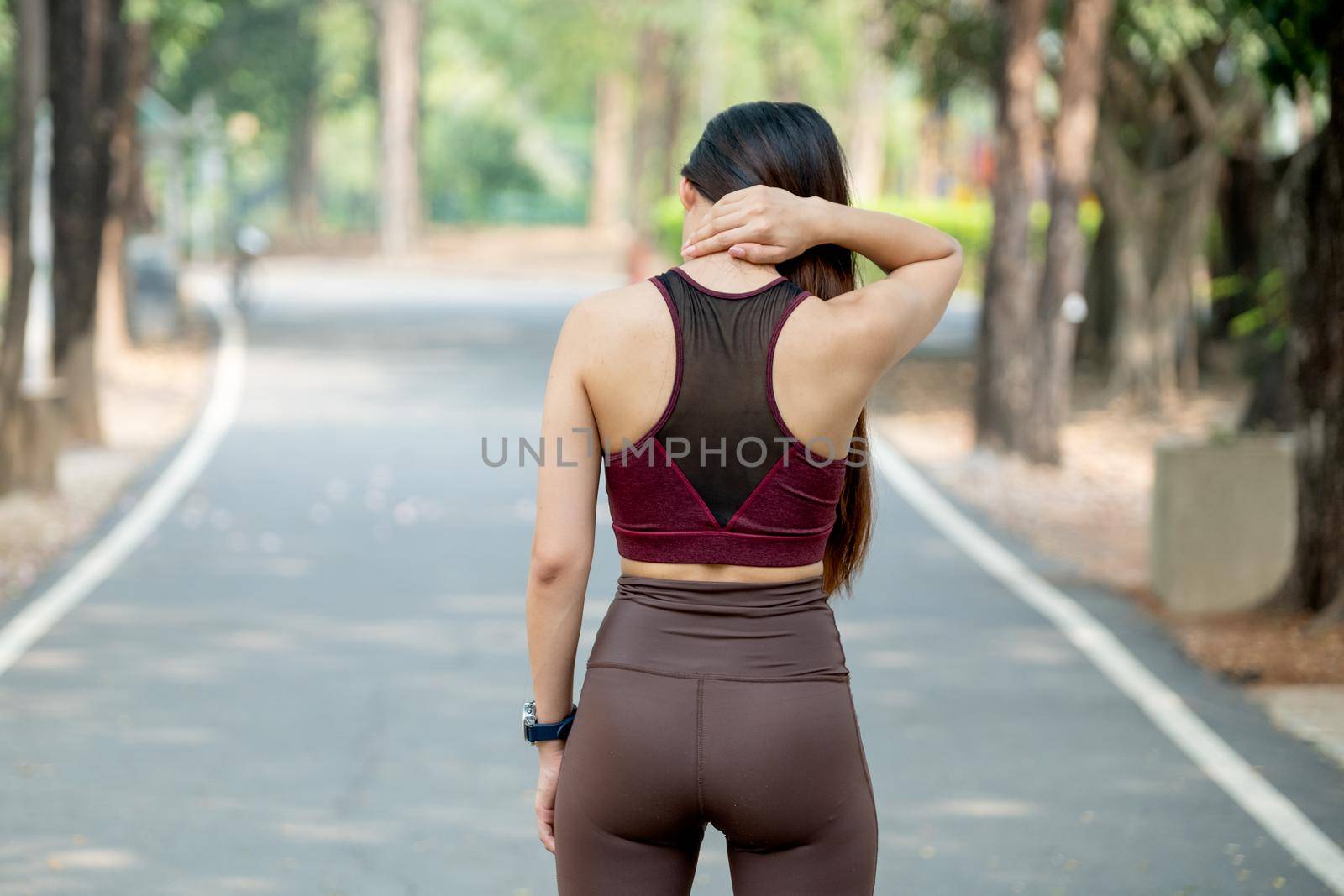 Back of sport woman touch her neck for action of pain after exercise in park or garden during morning.