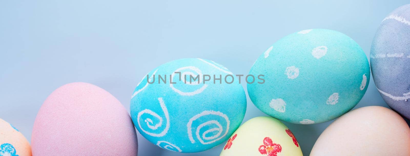 Colorful Easter eggs dyed by colored water with beautiful pattern on a pale blue background, design concept of holiday activity, top view, copy space. by ROMIXIMAGE