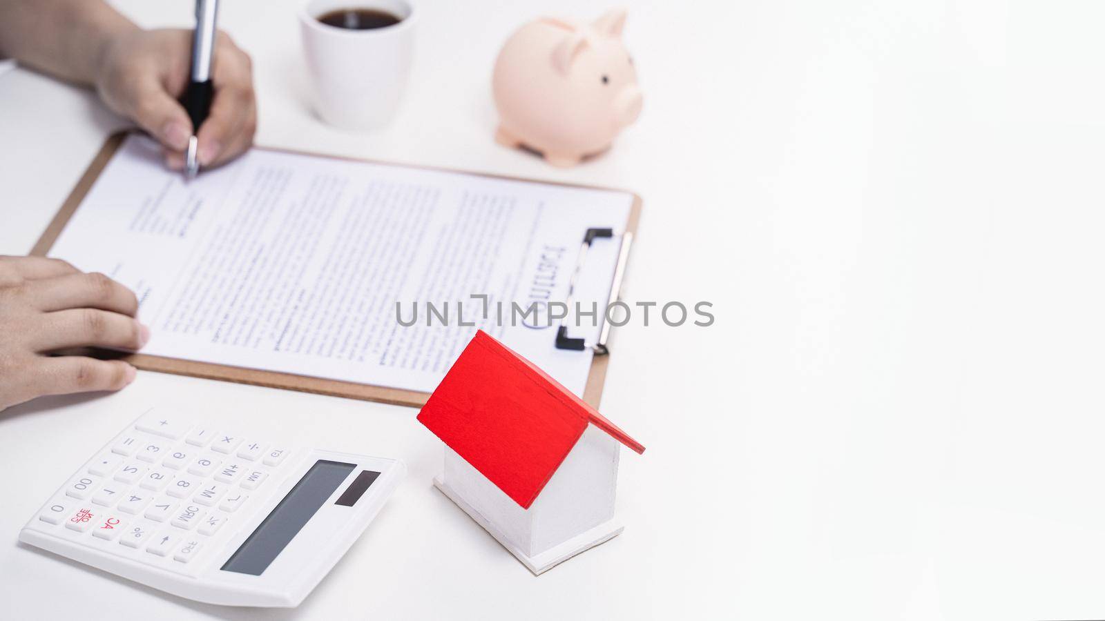 Business concept - Young Asian man in blue shirt calculates, signs agreement contract to buy a house loan payment, paying insurance, tax, close up.