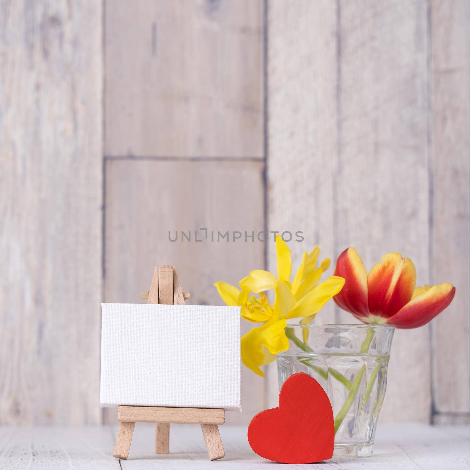 Tulip flower in glass vase with picture frame decor on wooden table background wall at home, close up, Mother's Day design concept. by ROMIXIMAGE