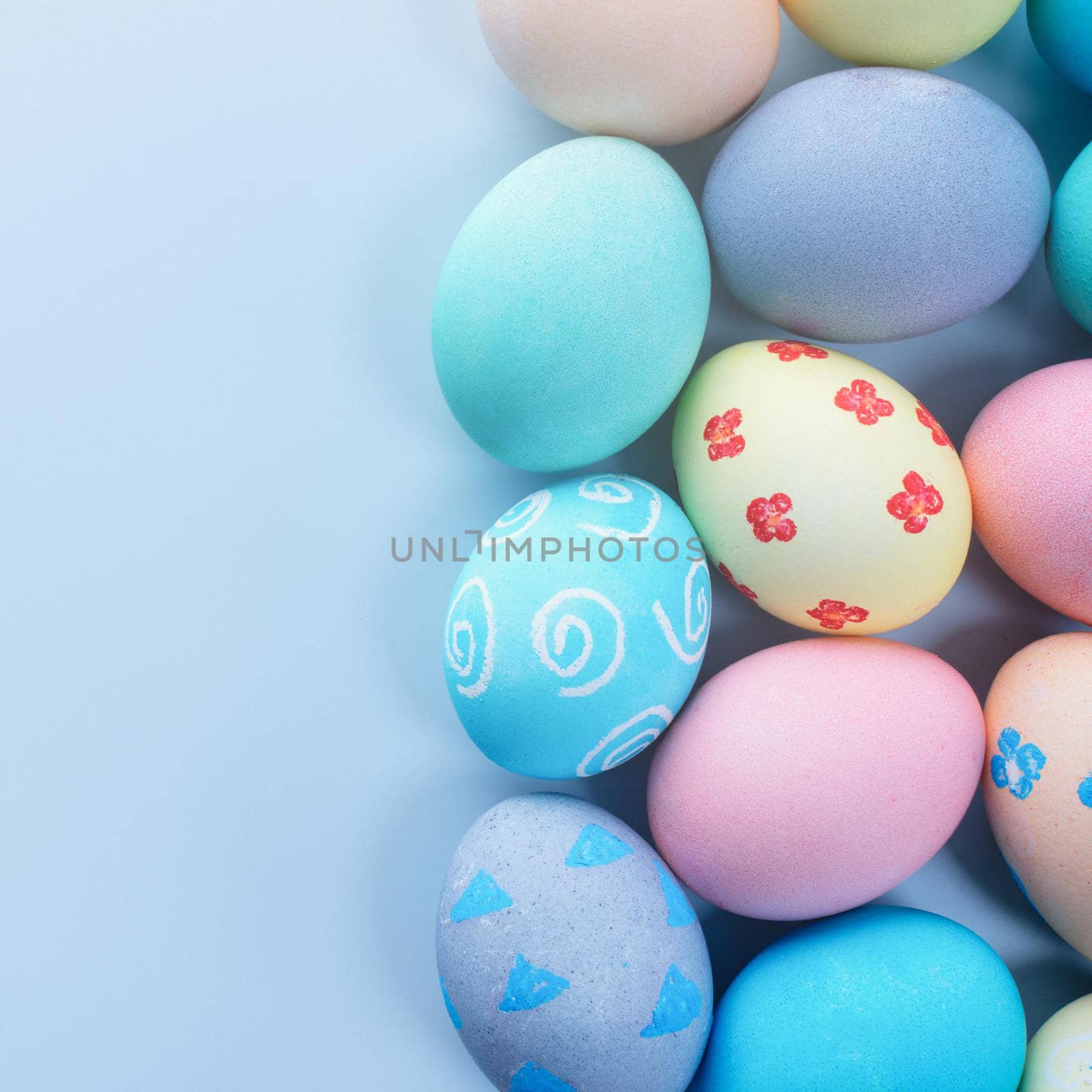 Colorful Easter eggs dyed by colored water with beautiful pattern on a pale blue background, design concept of holiday activity, top view, copy space. by ROMIXIMAGE