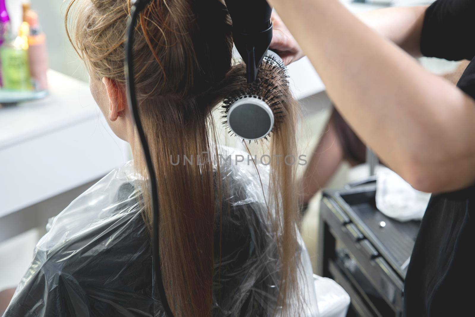 Close up of hairdressers hands drying long blond hair with blow dryer