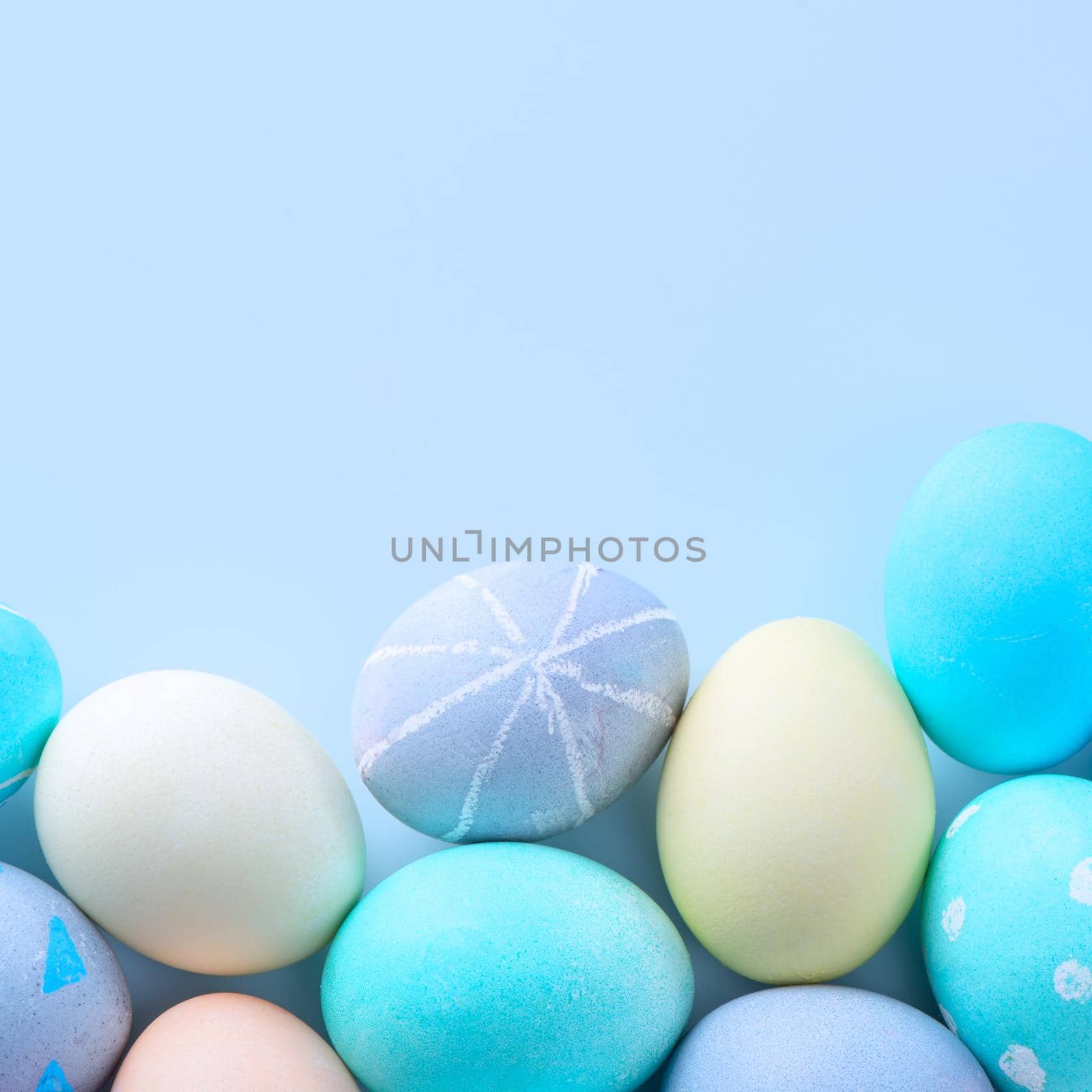 Colorful Easter hunting eggs dyed by colored water with beautiful pattern on pastel blue background, design concept of holiday, top view, copy space. by ROMIXIMAGE