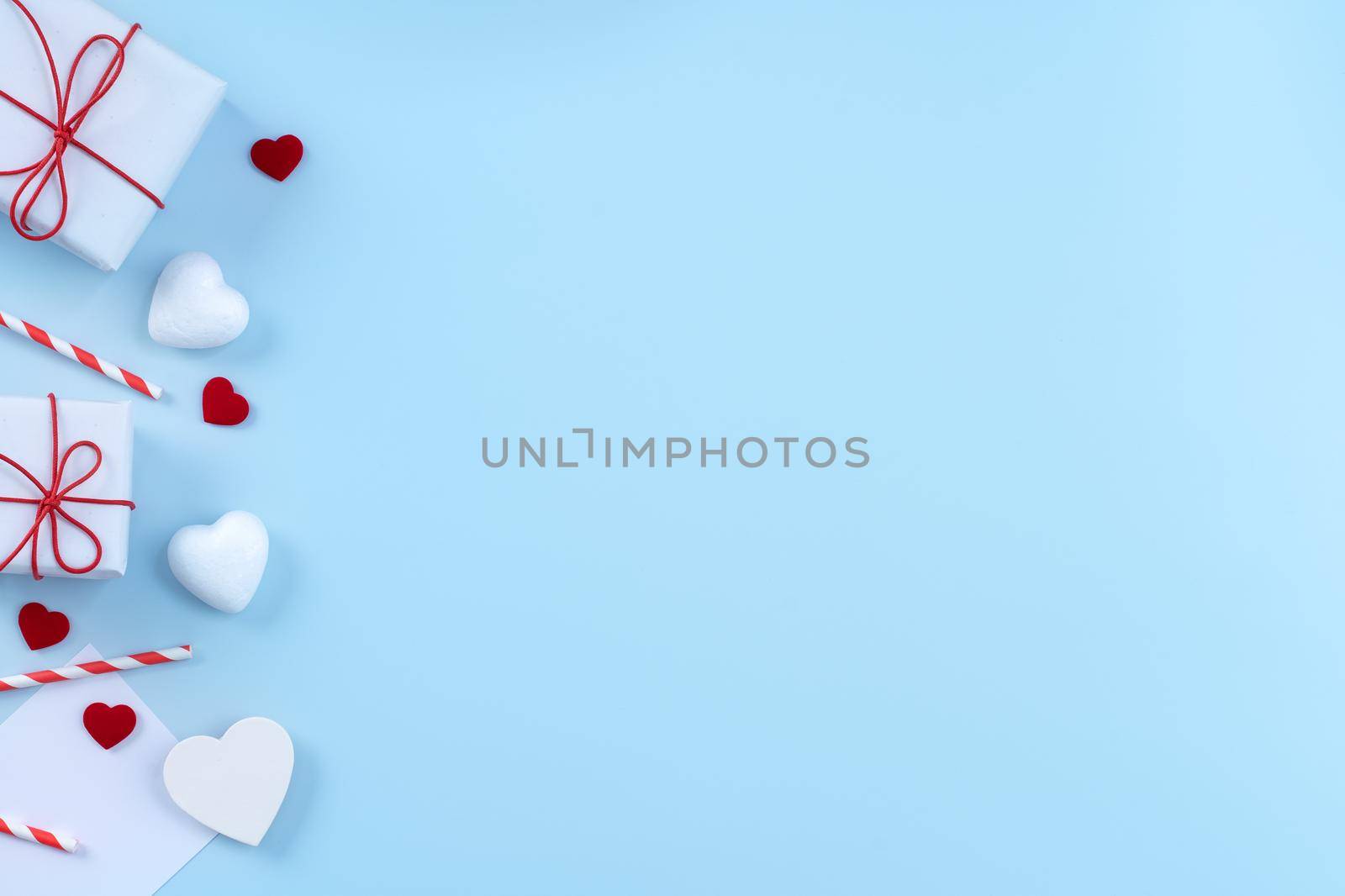 Valentine's Day, Mother's day art design concept - Red, white wrapped gift box isolated on pastel light blue color background, flat lay, top view.