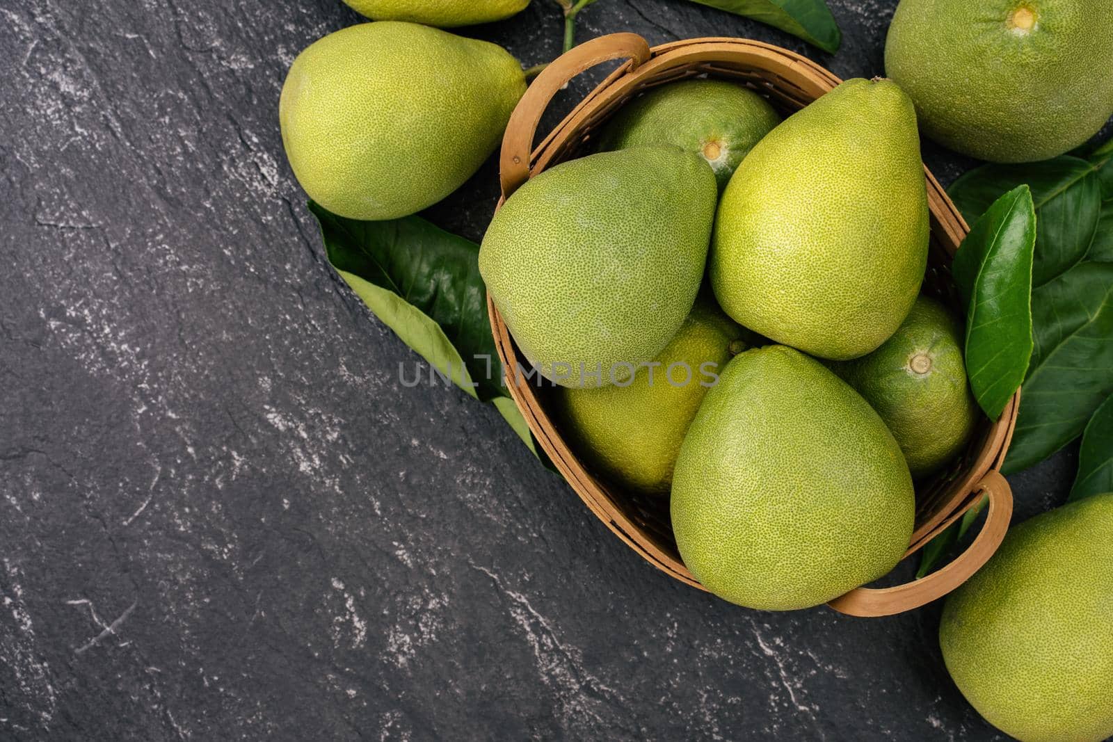 Fresh peeled pomelo, pummelo, grapefruit, shaddock on dark background in bamboo basket. Autumn seasonal fruit, top view, flat lay, tabletop shot. by ROMIXIMAGE