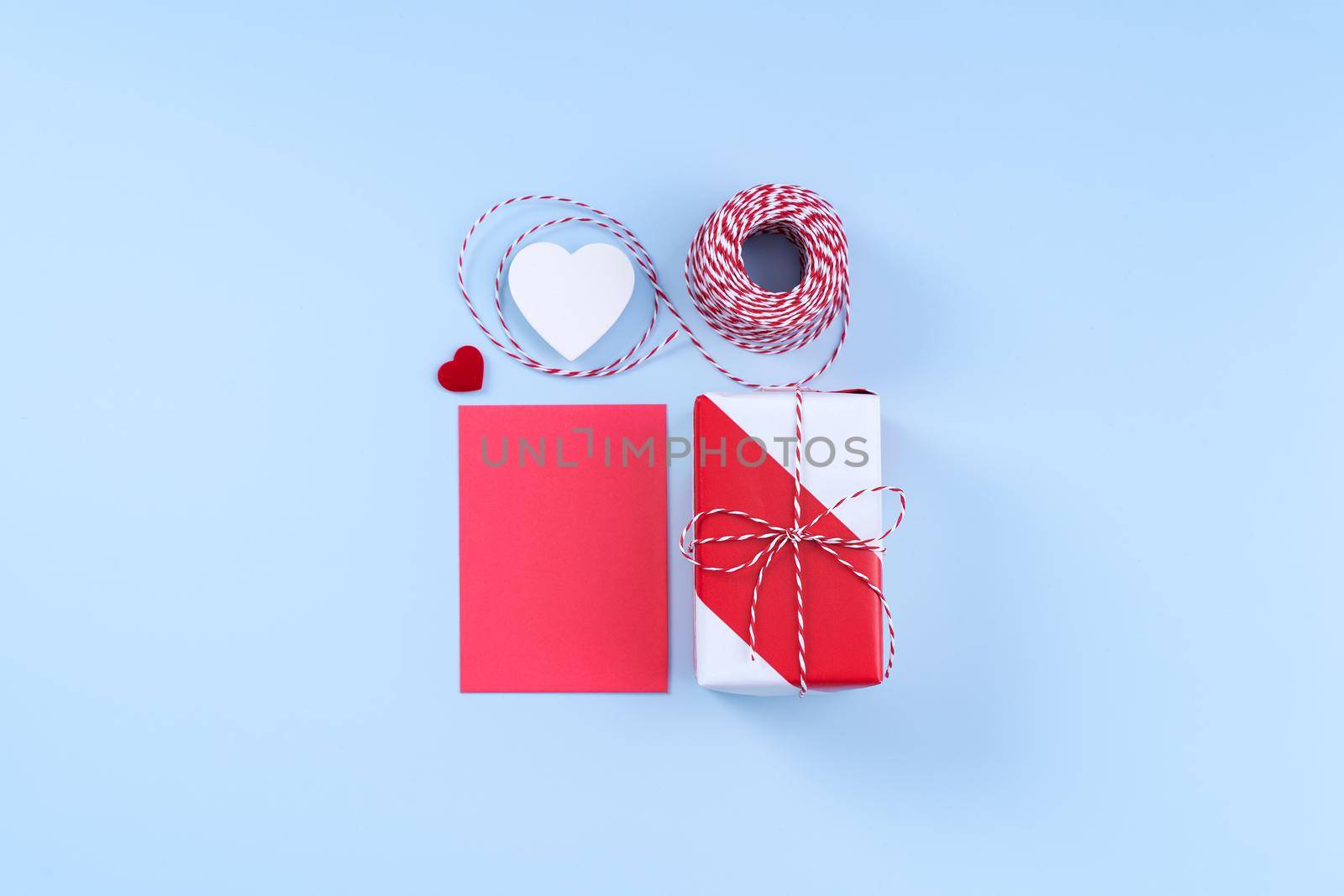 Valentine's Day, Mother's day art design concept - Red, white wrapped gift box isolated on pastel light blue color background, flat lay, top view. by ROMIXIMAGE