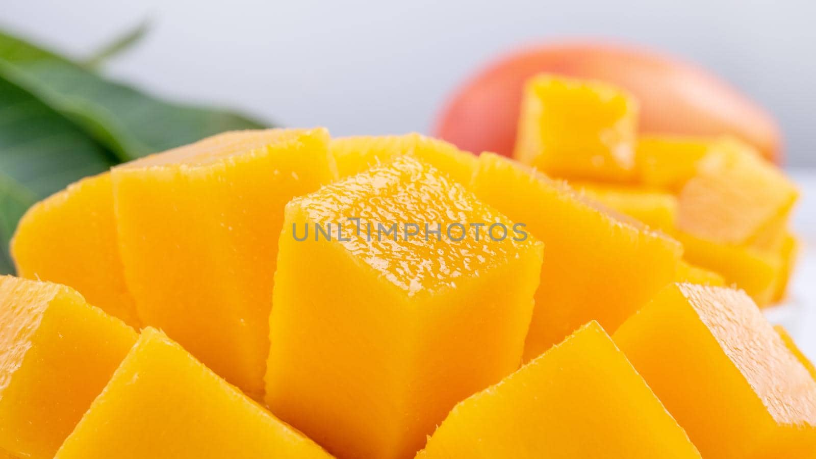Fresh mango,beautiful chopped fruit with green leaves on bright wooden table background. Tropical fruit design concept, close up, copy space.