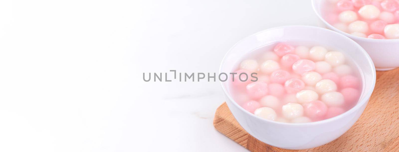 Tang yuan, tangyuan, delicious red and white rice dumpling balls in a small bowl. Asian traditional festive food for Chinese Winter Solstice Festival, close up. by ROMIXIMAGE