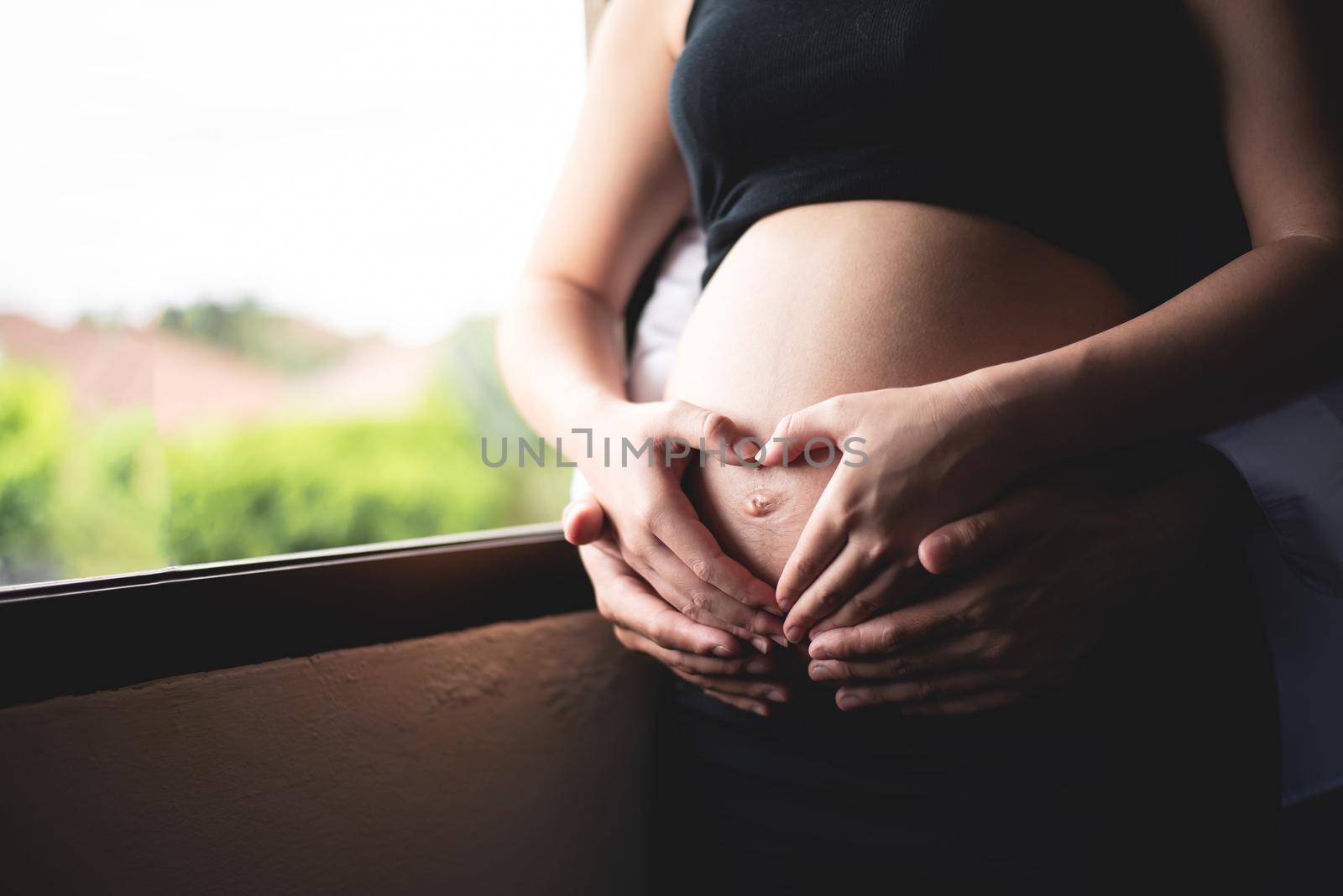 beautiful pregnant woman and her handsome husband hugging the tummy