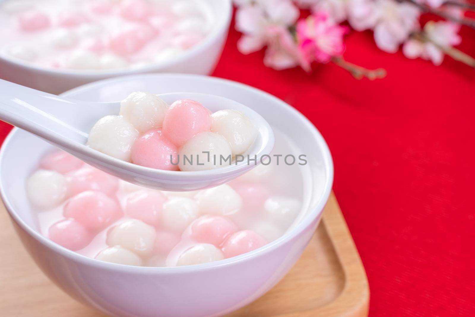 Tang yuan, tangyuan, delicious red and white rice dumpling balls in a small bowl on red background. Asian festive food for Chinese Winter Solstice Festival, close up. by ROMIXIMAGE