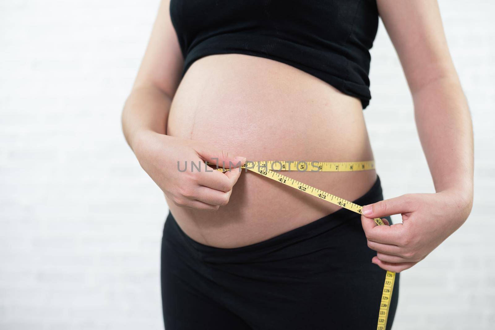 Pregnant woman measures belly circumference by Wmpix