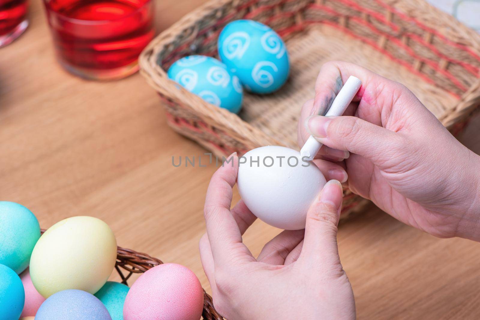 Easter eggs preparation - Young woman is drawing white egg with pastel wax crayon before dyeing colors at home kitchen table, close up, lifestyle by ROMIXIMAGE