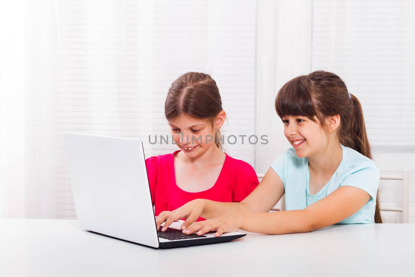 Two little girls using laptop and smiling