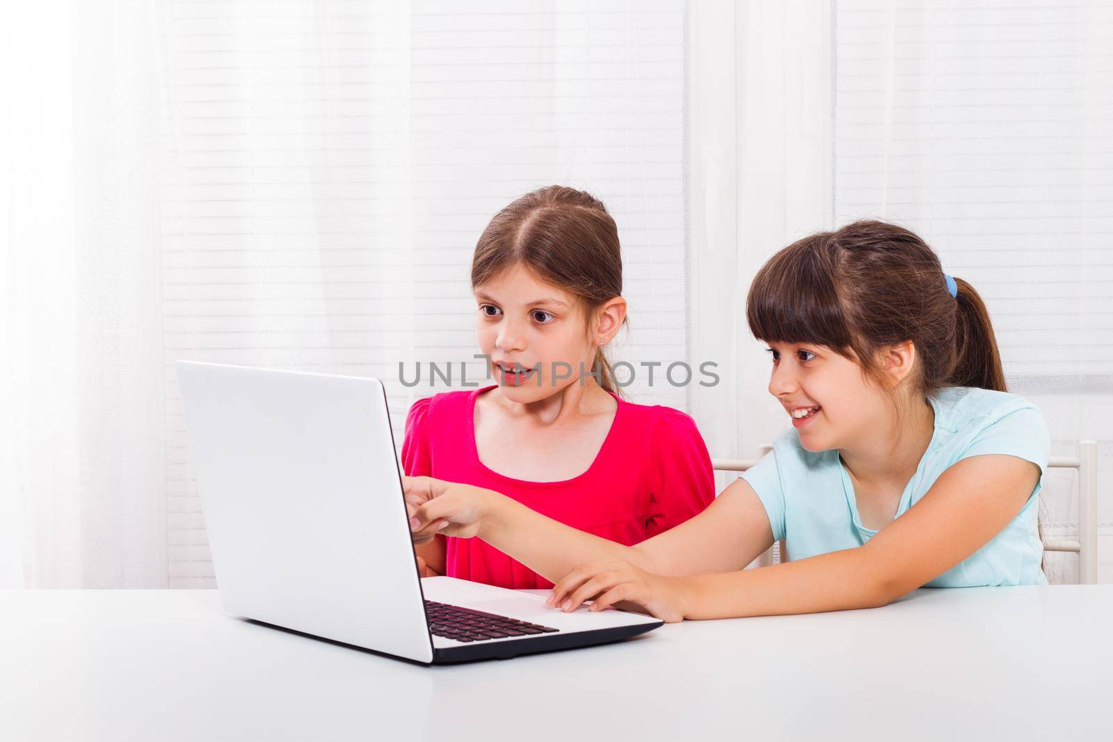 Surprised little girls working on laptop by Bazdar