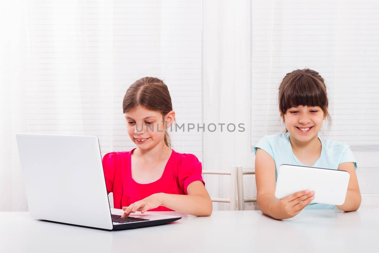Two little happy girls with laptop and tablet