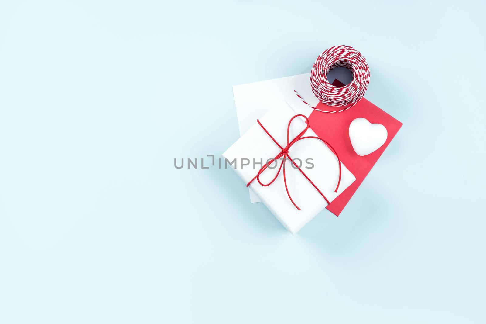 Valentine's Day, Mother's day handmade gift design concept - Wrapped gift box isolated on pastel light blue color background, flat lay, top view.