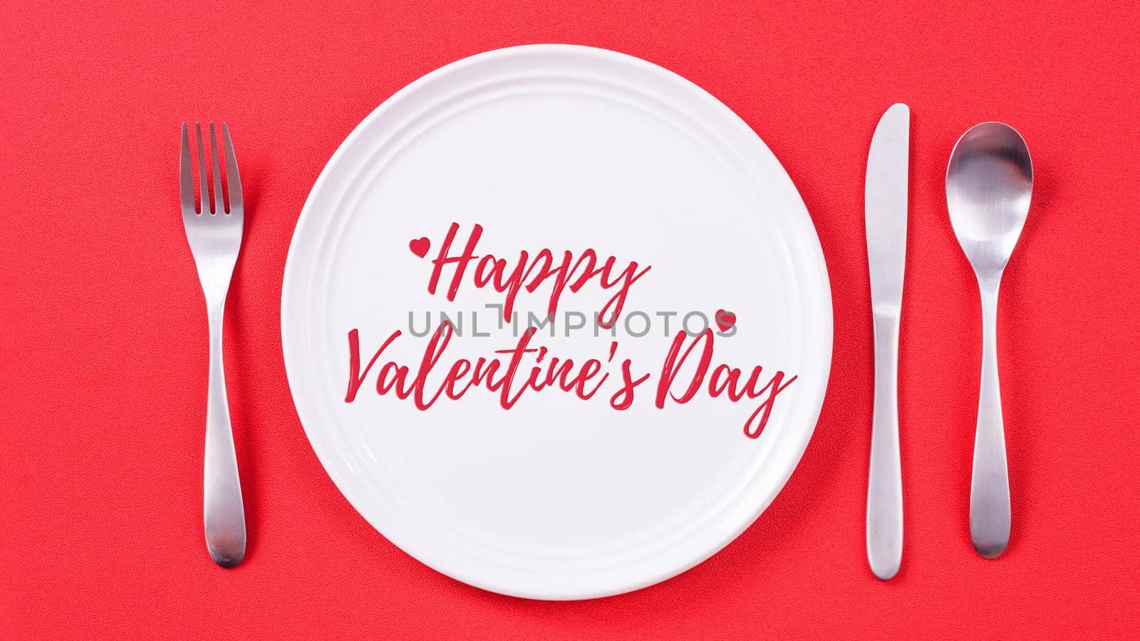 Valentine's Day holiday dating meal, banquet greeting card design concept - White plate with cutlery on red background, top view, flat lay.