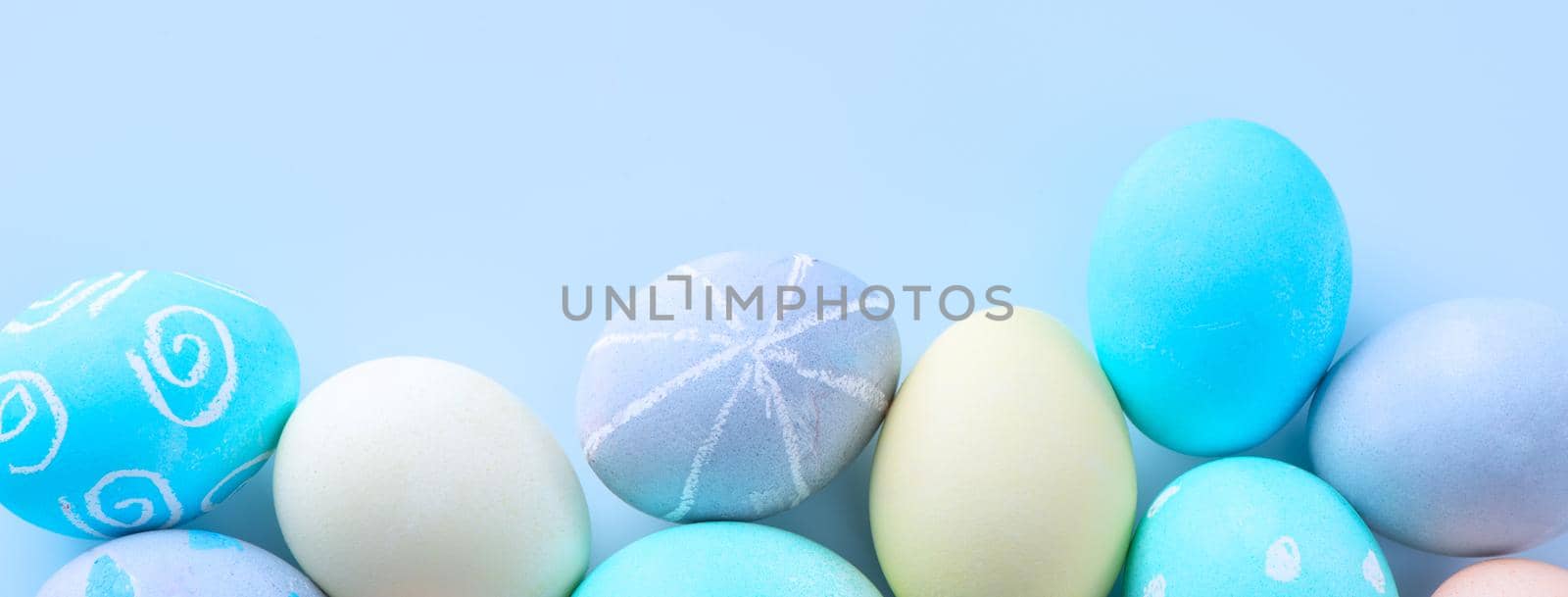 Colorful Easter eggs dyed by colored water with beautiful pattern on a pale blue background, design concept of holiday activity, top view, copy space.