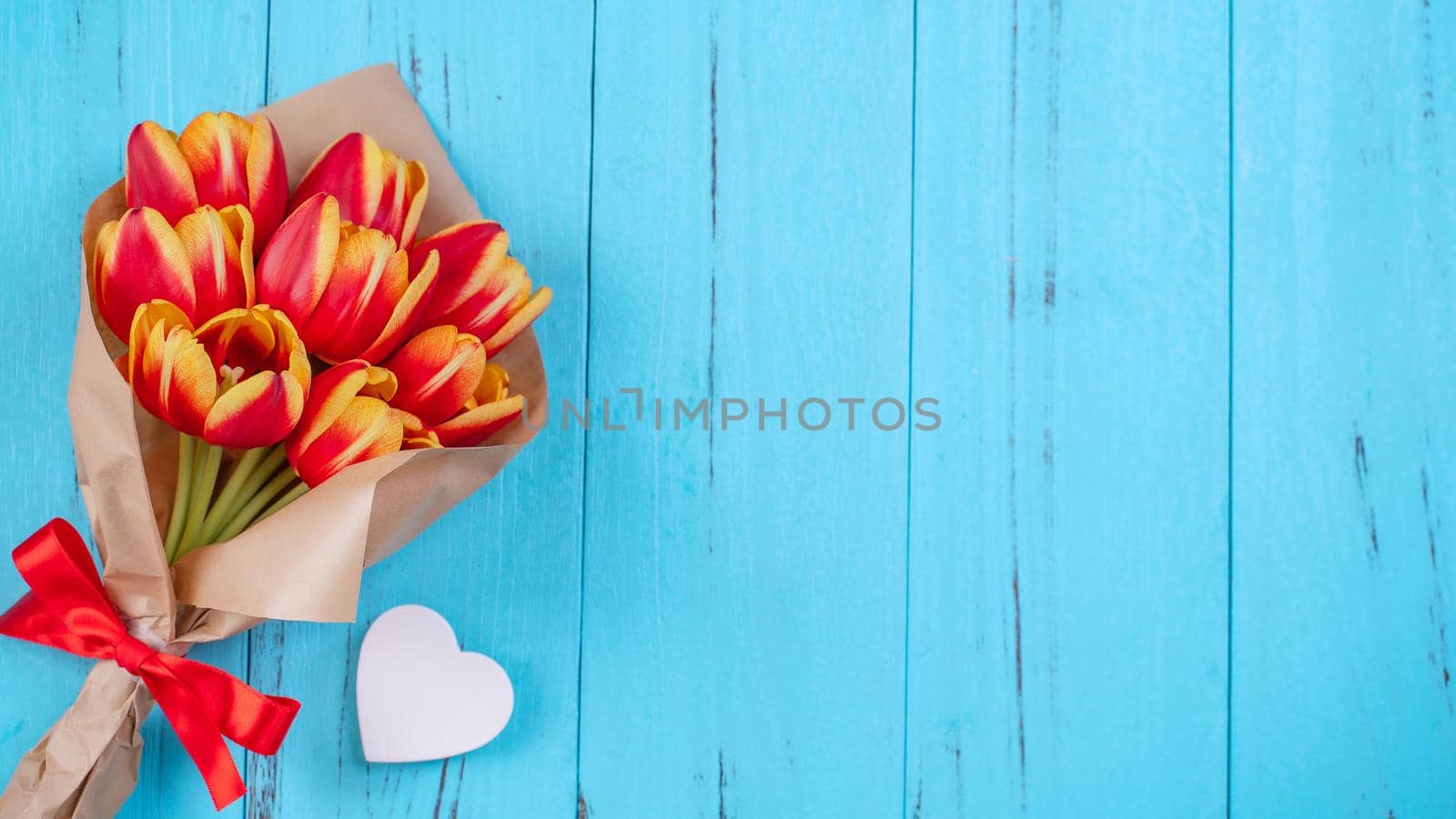 Tulip flower bunch, Mother's Day Design Concept - Beautiful Red, yellow bouquet isolated on blue wooden background, top view, flat lay, copy space by ROMIXIMAGE