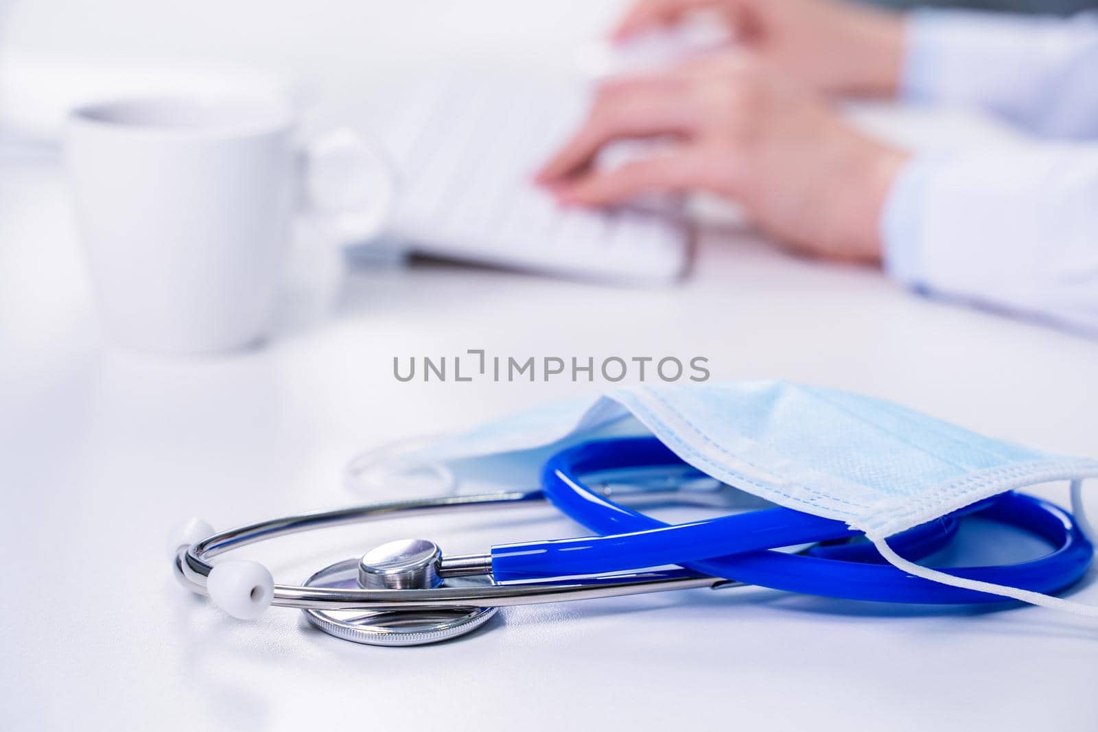 Business concept - Young female doctor woman working at office with computer, typing electronic medical record, white table background, close up, copy space