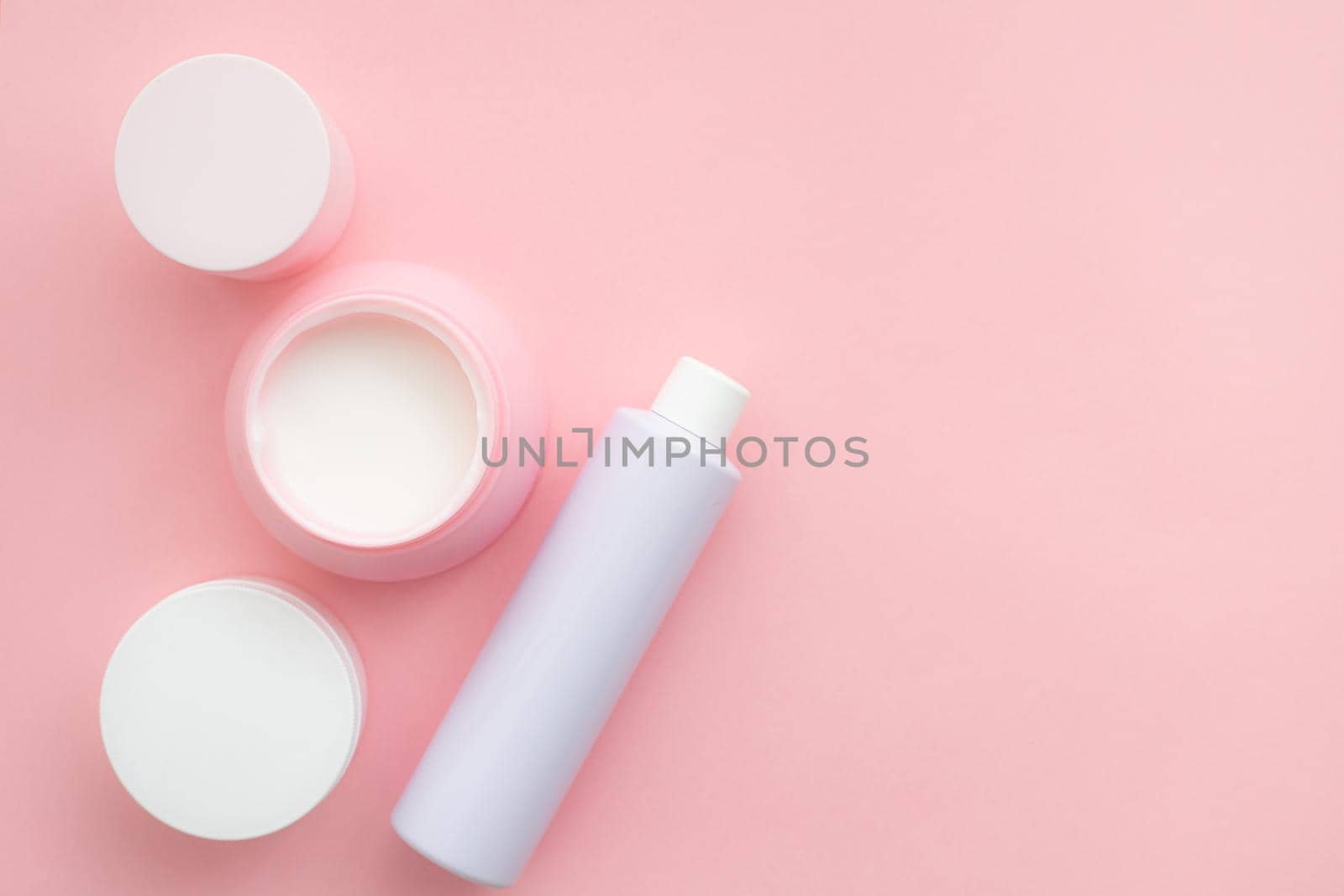 Layout on a pink cream background . Cosmetology. Care cosmetics. Skin care. Jars of cream. Pink background. Copy space. Article about the choice of cream. Spa. Spa treatments .