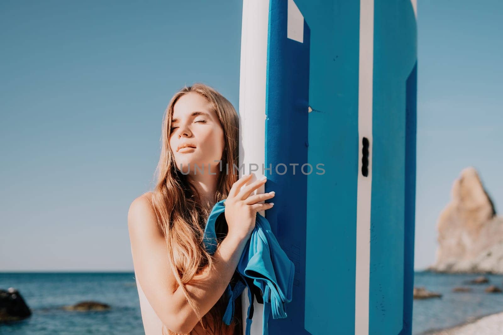 Close up shot of happy young caucasian woman looking at camera and smiling. Cute woman portrait in bikini posing on a volcanic rock high above the sea