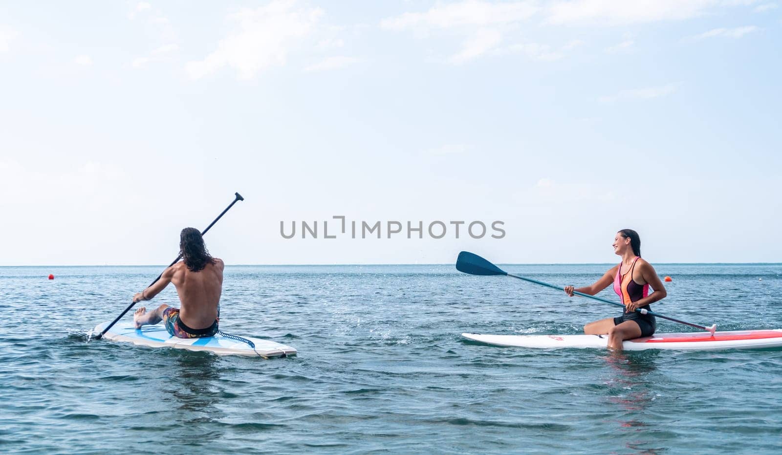 Woman sup yoga. Happy young sporty woman practising yoga pilates on paddle sup surfboard. Female stretching doing workout on sea water. Modern individual female outdoor summer sport activity