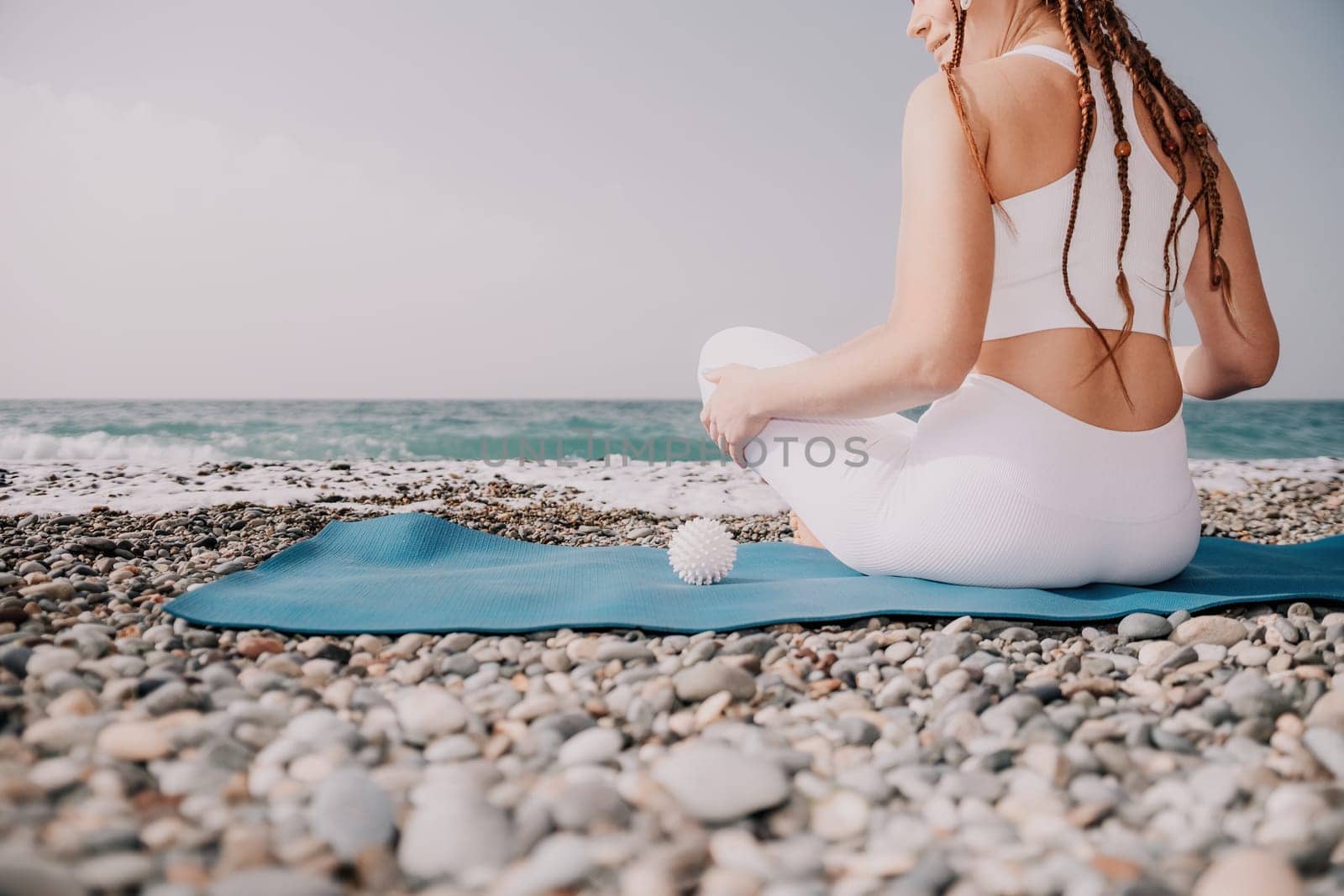 Close up Yoga Hand Gesture of Woman Doing an Outdoor meditation. Blurred sea background. Woman on yoga mat in beach meditation, mental health training or mind wellness by ocean, sea. Selective focus by panophotograph