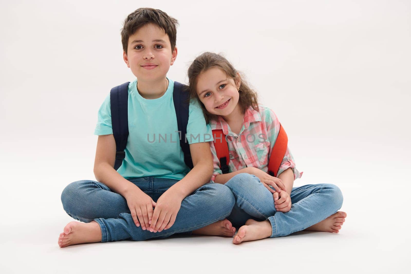 Happy diverse school kids with backpacks, wearing casual clothes, smiling broadly looking at camera, happy to start new academic year semester, isolated white studio background. Back to school concept